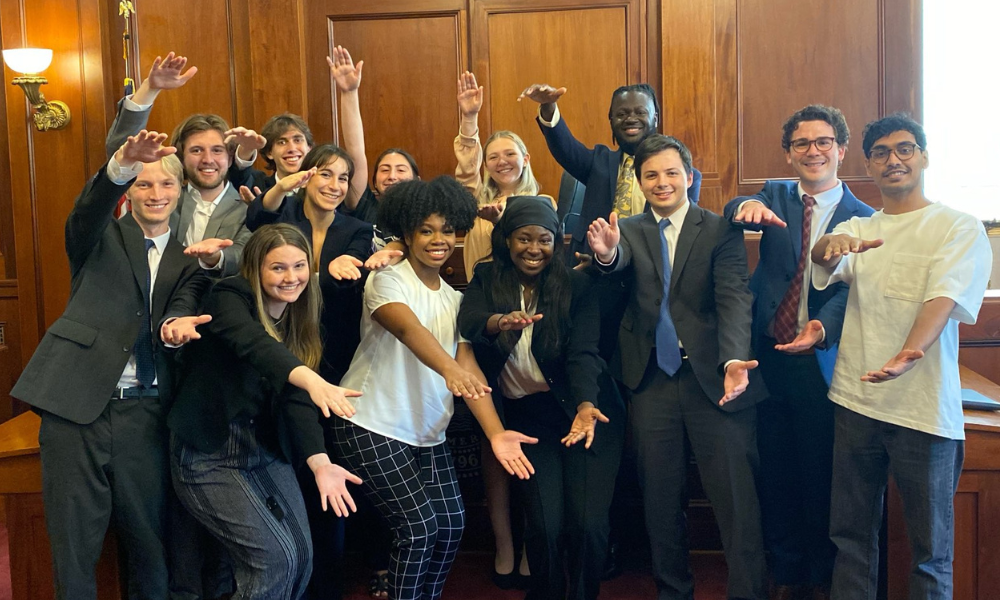 UF LitiGator team in courtroom doing the gator chomp with their arms.
