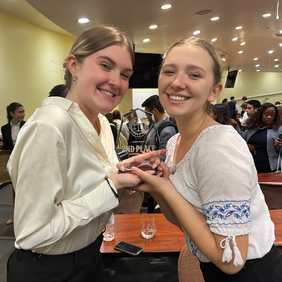 Two LitiGator team members holding the second place trophy they won at an FSU tournament 